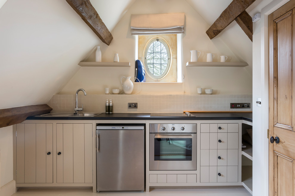 Inspiration for a small country l-shaped separate kitchen in Gloucestershire with a drop-in sink, beige cabinets, beige splashback, stainless steel appliances, no island, beige floor and black benchtop.