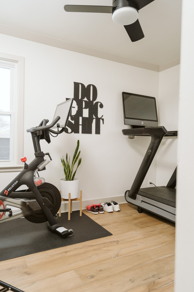 Cette image montre une petite salle de sport minimaliste multi-usage avec un mur blanc, parquet clair et un sol marron.