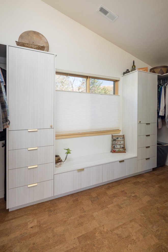 Photo of a medium sized gender neutral walk-in wardrobe in Other with flat-panel cabinets, light wood cabinets, cork flooring and a vaulted ceiling.