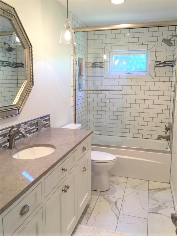 Small transitional 3/4 bathroom in Orange County with a two-piece toilet, multi-coloured tile, an undermount sink, recessed-panel cabinets, white cabinets, an alcove tub, a shower/bathtub combo, matchstick tile, white walls, marble floors and solid surface benchtops.