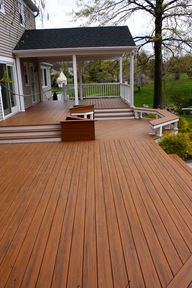This is an example of a large traditional backyard deck in New York with a container garden and a roof extension.