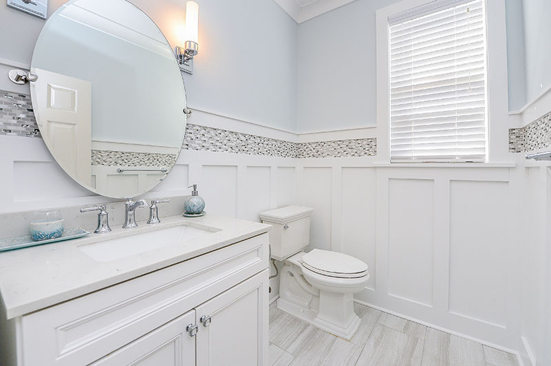 Inspiration for a small coastal cloakroom in Philadelphia with recessed-panel cabinets, white cabinets, black and white tiles, blue walls, wood-effect flooring, grey floors and a built in vanity unit.