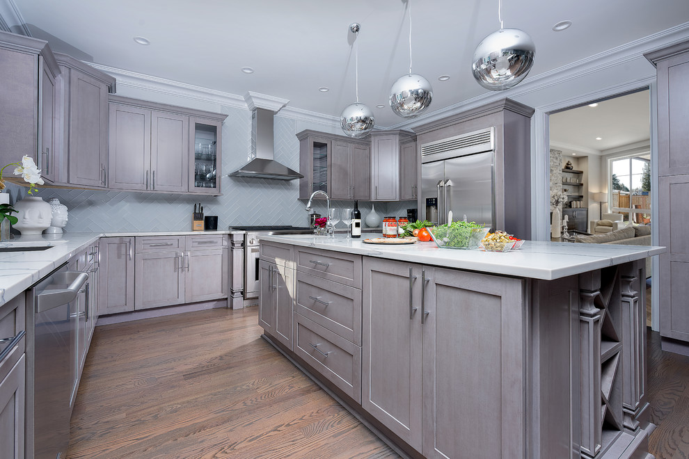 Design ideas for a large transitional u-shaped open plan kitchen in New York with grey cabinets, granite benchtops, stainless steel appliances, medium hardwood floors, with island, an undermount sink, shaker cabinets, grey splashback, glass tile splashback and brown floor.