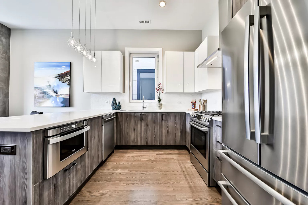 Inspiration for a small traditional u-shaped open plan kitchen in Chicago with an undermount sink, flat-panel cabinets, white cabinets, white splashback, stainless steel appliances, a peninsula and white benchtop.