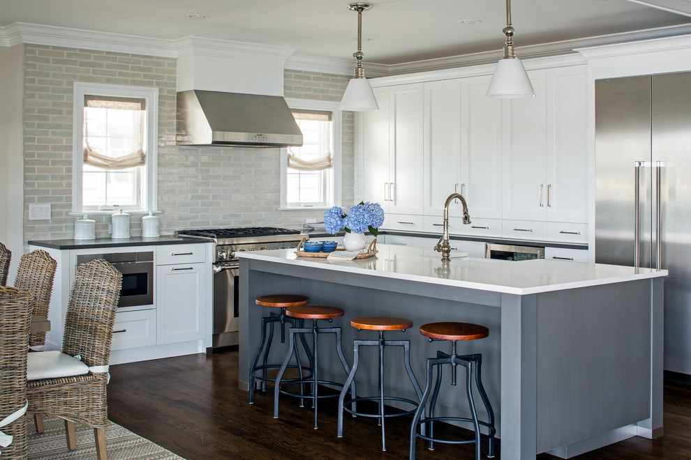 Eat-in kitchen - coastal l-shaped dark wood floor and brown floor eat-in kitchen idea with shaker cabinets, white cabinets, gray backsplash, subway tile backsplash, stainless steel appliances and an island