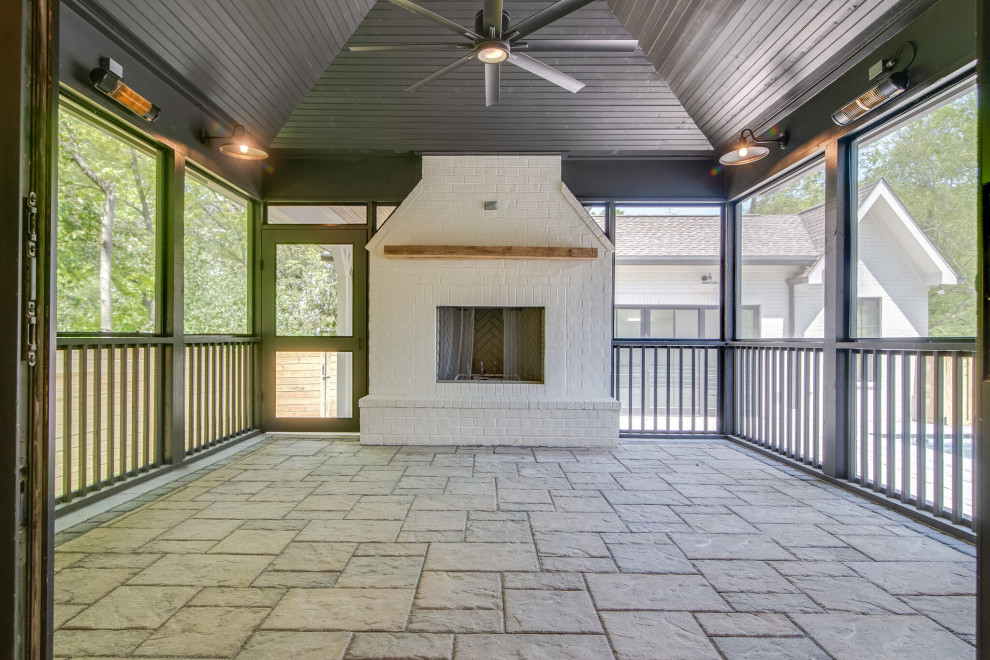 This is an example of a large transitional backyard verandah in Nashville with with fireplace, tile, a roof extension and wood railing.