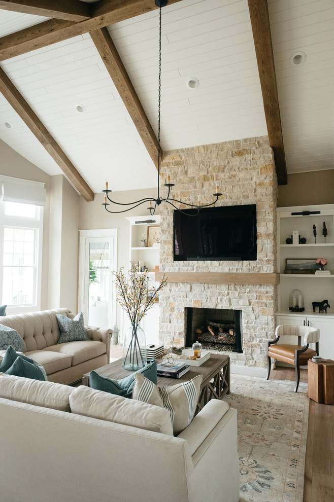 Inspiration for a large country enclosed family room in Detroit with beige walls, light hardwood floors, a standard fireplace, a stone fireplace surround, a built-in media wall and brown floor.