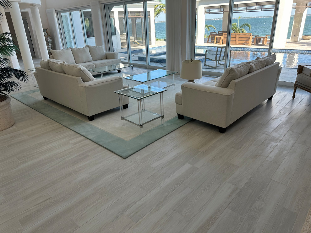 Large beach style formal open plan living room in Tampa with white walls, porcelain flooring, no tv, grey floors, wallpapered walls, a standard fireplace, a stone fireplace surround and a vaulted ceiling.