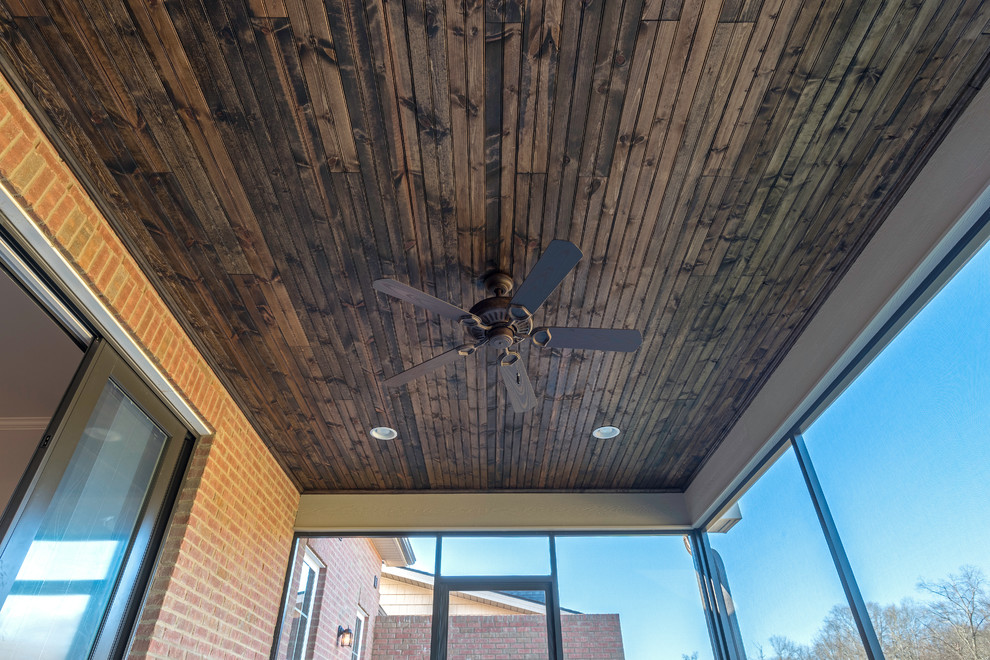 Mid-sized transitional concrete screened-in back porch idea with a roof extension