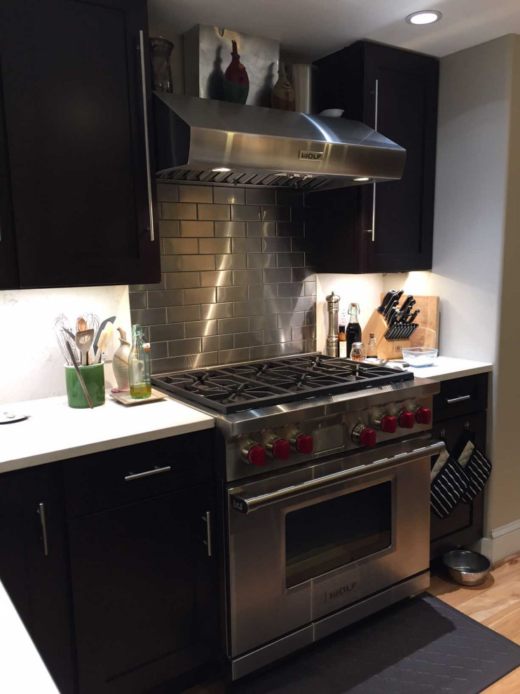 Transitional light wood floor eat-in kitchen photo in Atlanta with metallic backsplash, metal backsplash, stainless steel appliances, shaker cabinets, black cabinets and white countertops
