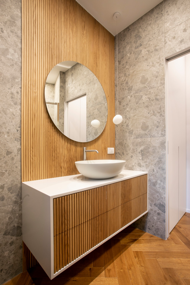 Photo of a medium sized modern shower room bathroom in Milan with grey cabinets, an alcove shower, a wall mounted toilet, grey tiles, porcelain tiles, grey walls, dark hardwood flooring, a vessel sink, solid surface worktops, brown floors, a sliding door, white worktops, a single sink, a floating vanity unit, a drop ceiling and wood walls.