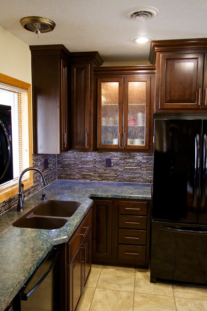 Example of a mid-sized u-shaped kitchen design with an undermount sink, dark wood cabinets, laminate countertops, multicolored backsplash, glass tile backsplash, black appliances and an island