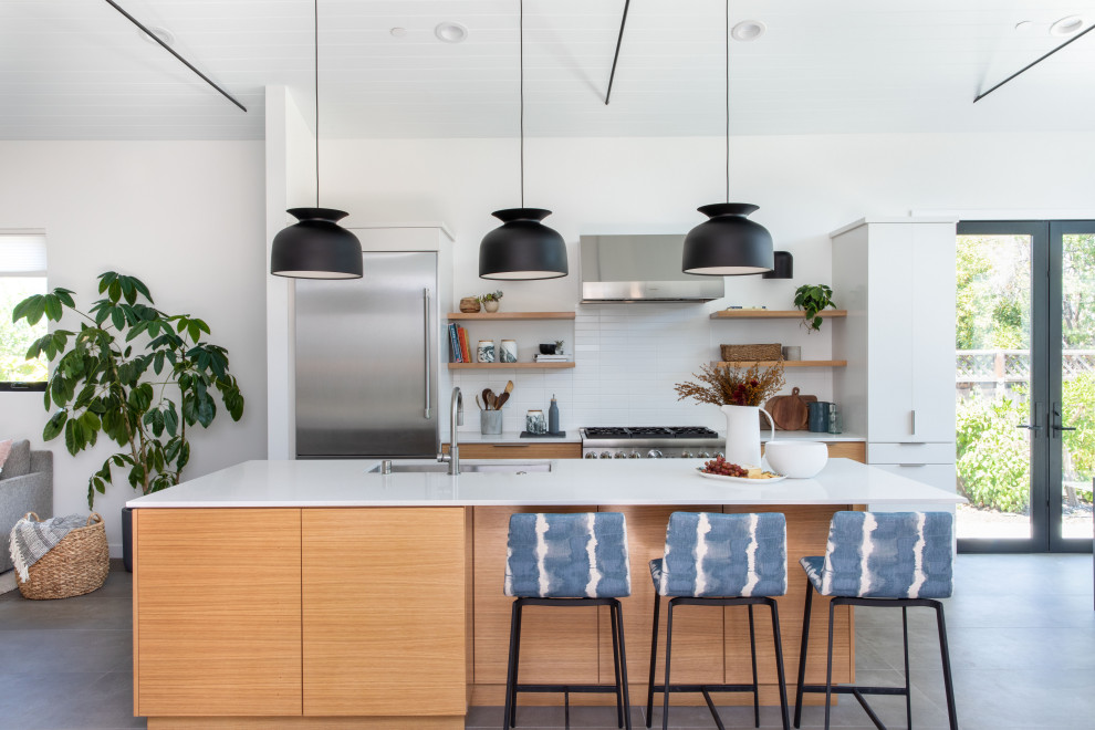 Design ideas for a mid-sized midcentury galley eat-in kitchen in San Francisco with a drop-in sink, flat-panel cabinets, light wood cabinets, quartz benchtops, white splashback, ceramic splashback, stainless steel appliances, porcelain floors, with island, grey floor, white benchtop and timber.