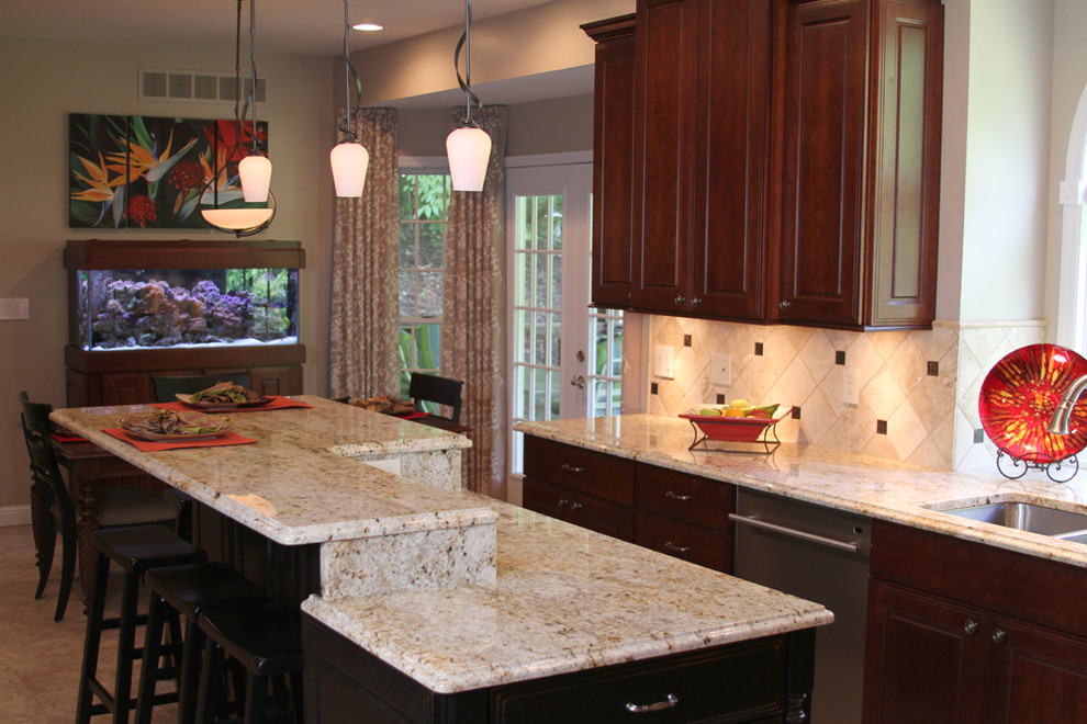 Inspiration for a mid-sized traditional l-shaped eat-in kitchen in St Louis with an undermount sink, raised-panel cabinets, brown cabinets, granite benchtops, beige splashback, travertine splashback, stainless steel appliances, porcelain floors, with island and beige floor.