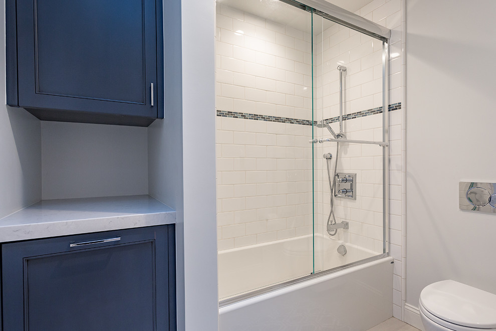 Inspiration for a transitional 3/4 bathroom in San Francisco with beaded inset cabinets, blue cabinets, an alcove tub, a shower/bathtub combo, white walls, marble benchtops and a sliding shower screen.