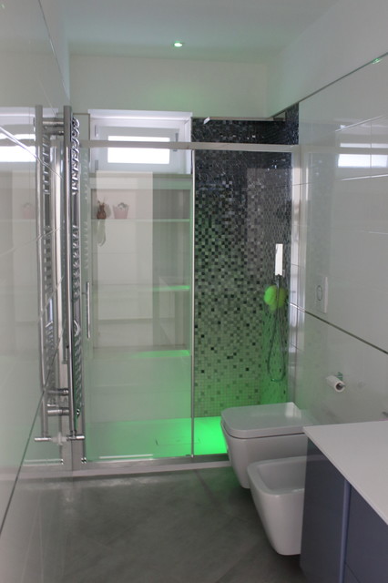 Immagine di una stanza da bagno con doccia design di medie dimensioni con ante lisce, ante grigie, doccia a filo pavimento, WC a due pezzi, piastrelle bianche, piastrelle in gres porcellanato, pareti bianche, pavimento in gres porcellanato, lavabo integrato, top in superficie solida, pavimento grigio, porta doccia scorrevole e top bianco