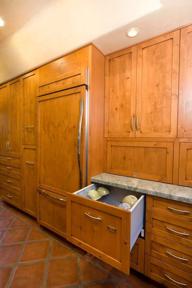 Photo of an eclectic galley separate kitchen in Santa Barbara with an integrated sink, shaker cabinets, medium wood cabinets, green splashback, stone tile splashback, panelled appliances, granite benchtops, terra-cotta floors and no island.