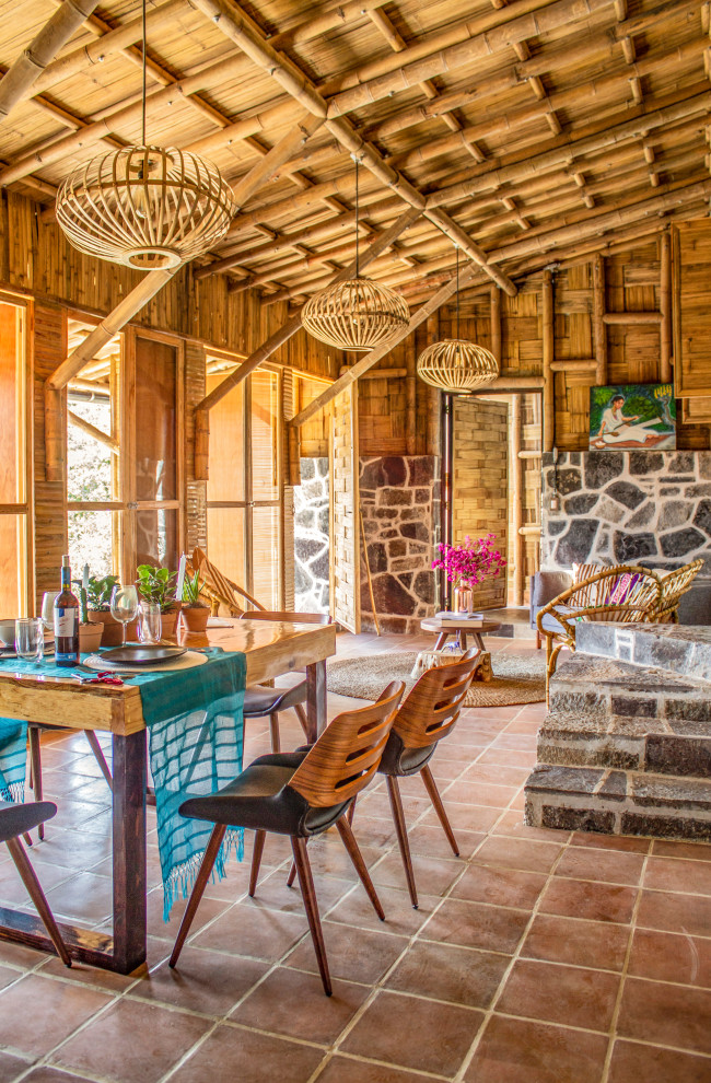 Cette image montre une salle à manger ouverte sur le salon chalet en bois de taille moyenne avec un mur marron, tomettes au sol, un sol rouge et un plafond en bois.