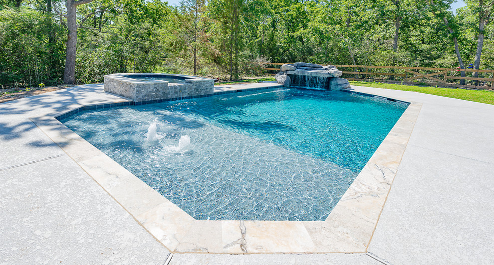 Large traditional backyard custom-shaped natural pool in Other with a hot tub and concrete slab.