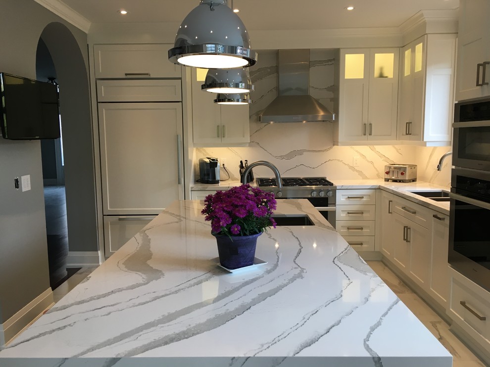 Large transitional l-shaped separate kitchen in Toronto with an undermount sink, shaker cabinets, white cabinets, quartz benchtops, white splashback, stone slab splashback, stainless steel appliances, porcelain floors, with island, white floor and white benchtop.