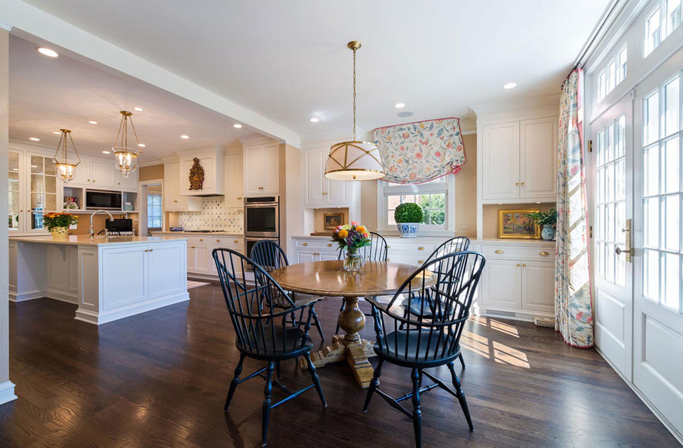 Inspiration for a mid-sized transitional galley dark wood floor and brown floor eat-in kitchen remodel in Chicago with an undermount sink, recessed-panel cabinets, white cabinets, solid surface countertops, white backsplash, ceramic backsplash, stainless steel appliances and an island