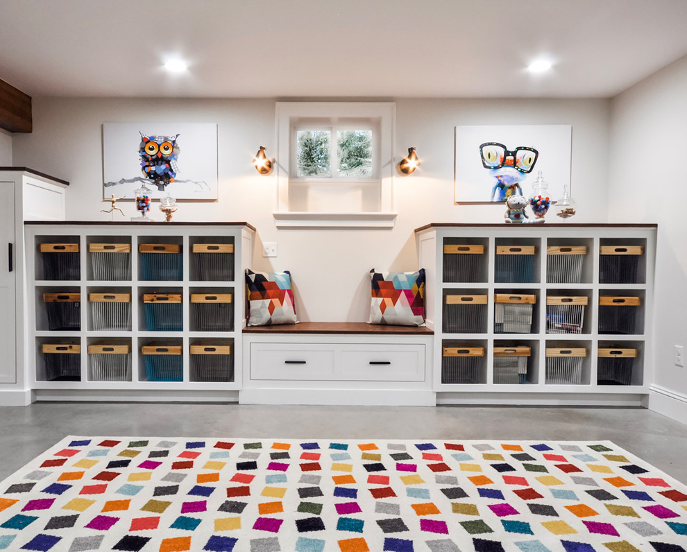 This is an example of a large transitional gender-neutral kids' playroom for kids 4-10 years old in Newark with white walls, concrete floors and grey floor.