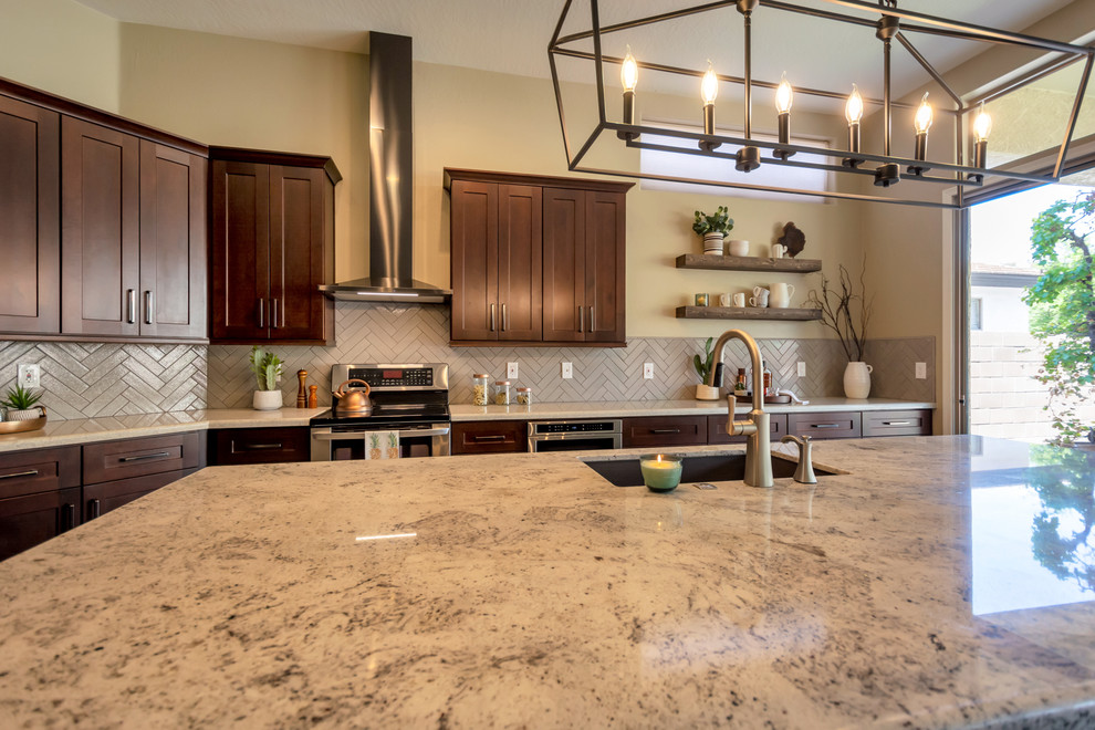 Open concept kitchen - mid-sized transitional l-shaped porcelain tile and brown floor open concept kitchen idea in Phoenix with a single-bowl sink, shaker cabinets, brown cabinets, granite countertops, gray backsplash, brick backsplash, stainless steel appliances, an island and multicolored countertops