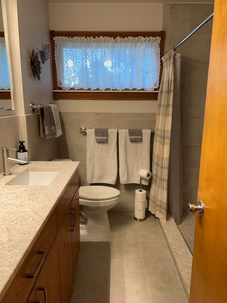Design ideas for a small contemporary bathroom in Detroit with flat-panel cabinets, medium wood cabinets, an alcove shower, a two-piece toilet, grey tiles, ceramic tiles, white walls, porcelain flooring, a submerged sink, engineered stone worktops, grey floors, a shower curtain, beige worktops, a wall niche, a single sink and a built in vanity unit.