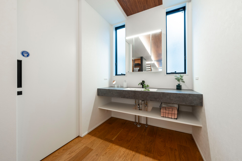 Mittelgroße Moderne Gästetoilette mit grauen Schränken, braunem Boden, freistehendem Waschtisch, Tapetendecke und Tapetenwänden in Sonstige