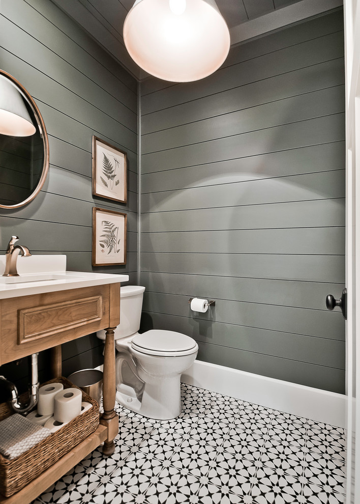 Photo of a large country powder room in Other with furniture-like cabinets, a two-piece toilet, an undermount sink, engineered quartz benchtops, white benchtops, medium wood cabinets, grey walls and multi-coloured floor.