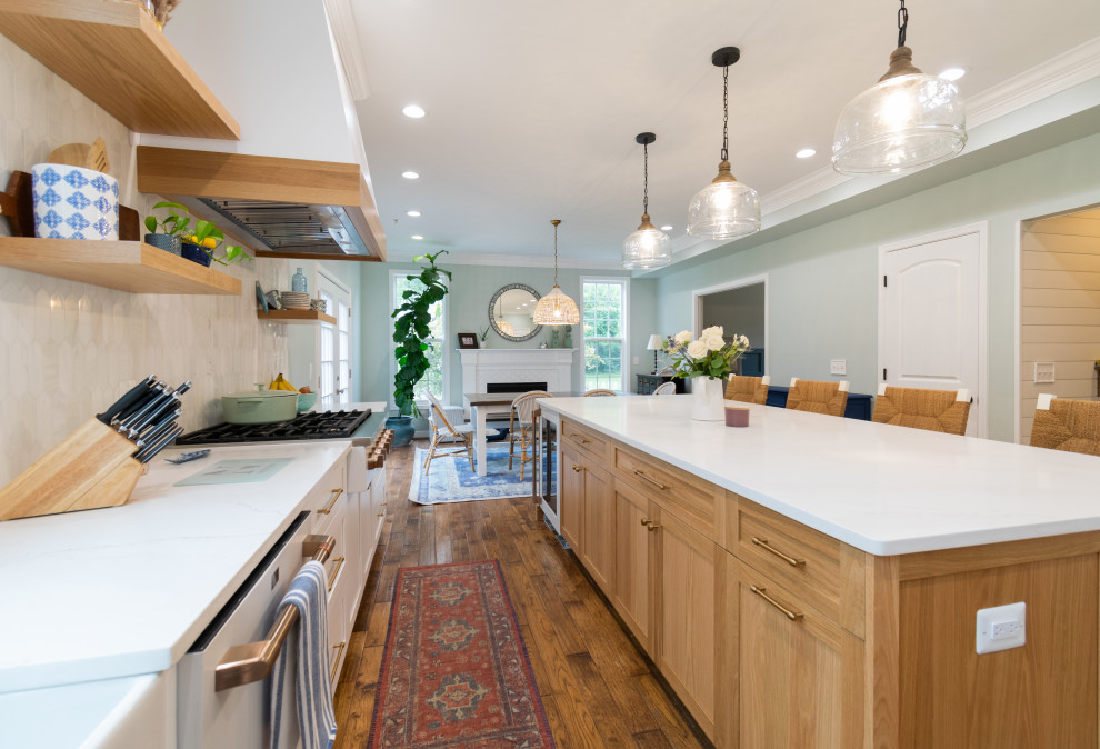 Inspiration for a medium sized rural l-shaped kitchen/diner in Baltimore with a belfast sink, shaker cabinets, light wood cabinets, engineered stone countertops, multi-coloured splashback, ceramic splashback, white appliances, light hardwood flooring, an island, brown floors and multicoloured worktops.