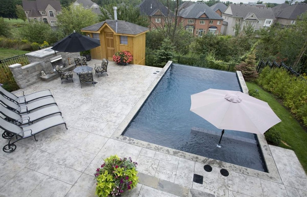 Design ideas for a small contemporary backyard rectangular lap pool in Toronto with a pool house and stamped concrete.