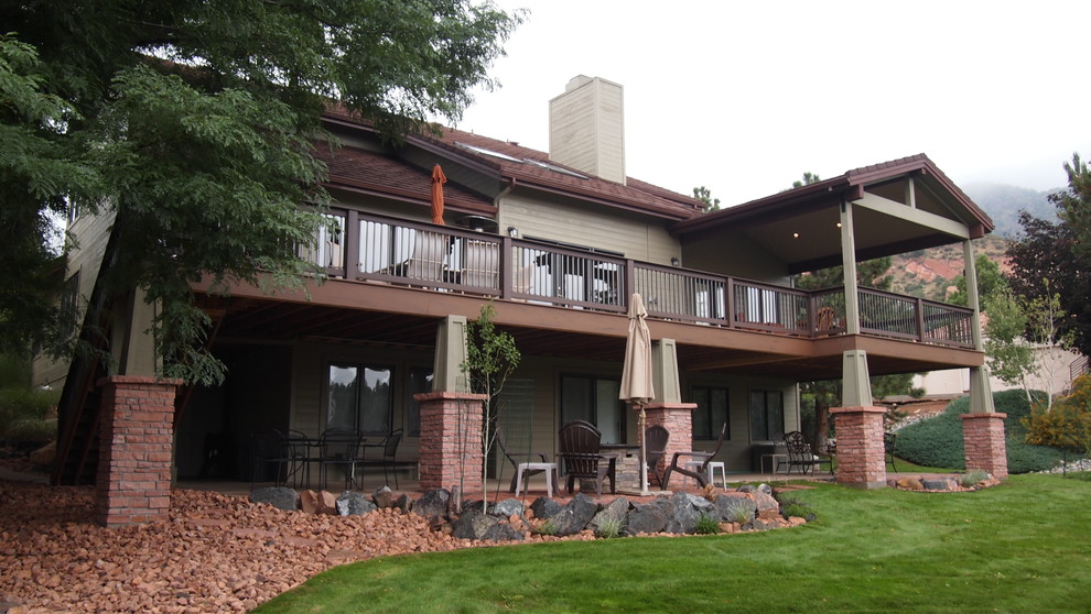 Photo of a large transitional backyard deck in Denver with a roof extension.