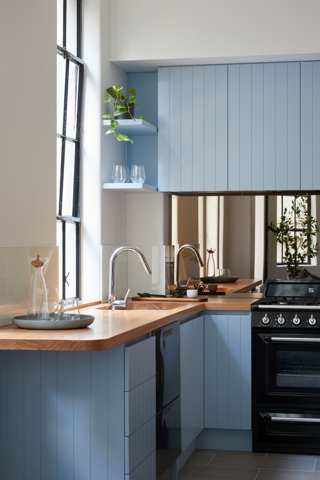 Design ideas for a mid-sized contemporary l-shaped eat-in kitchen in Melbourne with a double-bowl sink, blue cabinets, wood benchtops, metallic splashback, mirror splashback, stainless steel appliances, ceramic floors, no island, brown floor and raised-panel cabinets.