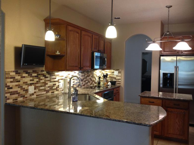 Example of a mid-sized u-shaped ceramic tile enclosed kitchen design with an undermount sink, raised-panel cabinets, medium tone wood cabinets, brown backsplash, matchstick tile backsplash, stainless steel appliances and an island