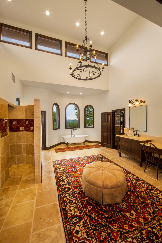 This is an example of a large mediterranean master bathroom in Austin with recessed-panel cabinets, medium wood cabinets, terra-cotta tile, granite benchtops, a claw-foot tub, white walls, travertine floors, an undermount sink and an open shower.