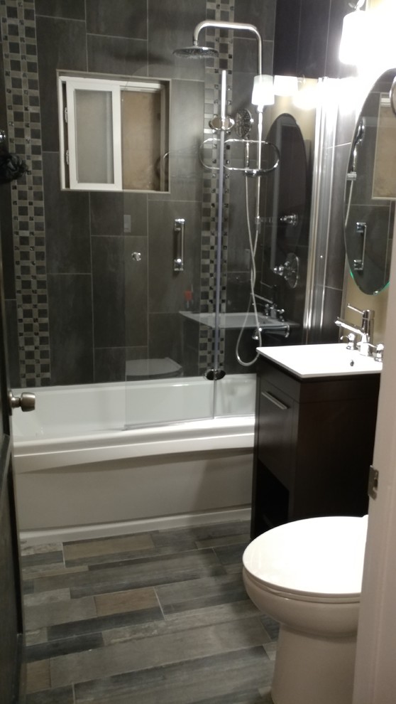 This is an example of a small industrial master bathroom in Los Angeles with flat-panel cabinets, dark wood cabinets, a hot tub, a shower/bathtub combo, a two-piece toilet, gray tile, pebble tile, multi-coloured walls, porcelain floors, a console sink, multi-coloured floor, a hinged shower door and white benchtops.