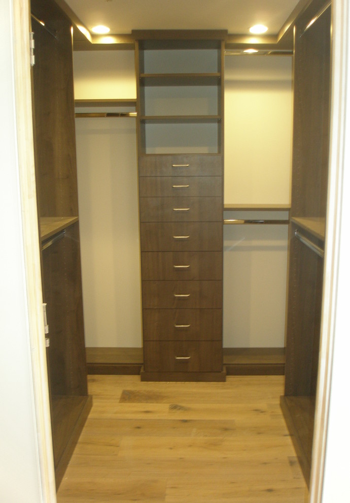 Photo of a small arts and crafts men's walk-in wardrobe in Los Angeles with flat-panel cabinets, dark wood cabinets, light hardwood floors and brown floor.