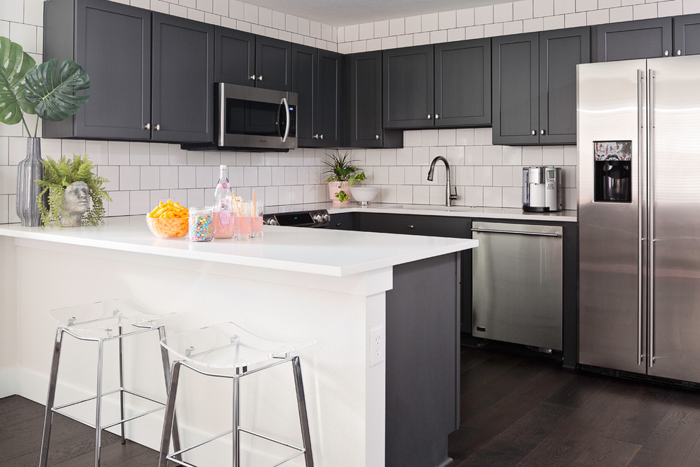 Eat-in kitchen - small transitional u-shaped dark wood floor and brown floor eat-in kitchen idea in Orlando with an undermount sink, shaker cabinets, gray cabinets, quartz countertops, white backsplash, subway tile backsplash, stainless steel appliances, an island and white countertops
