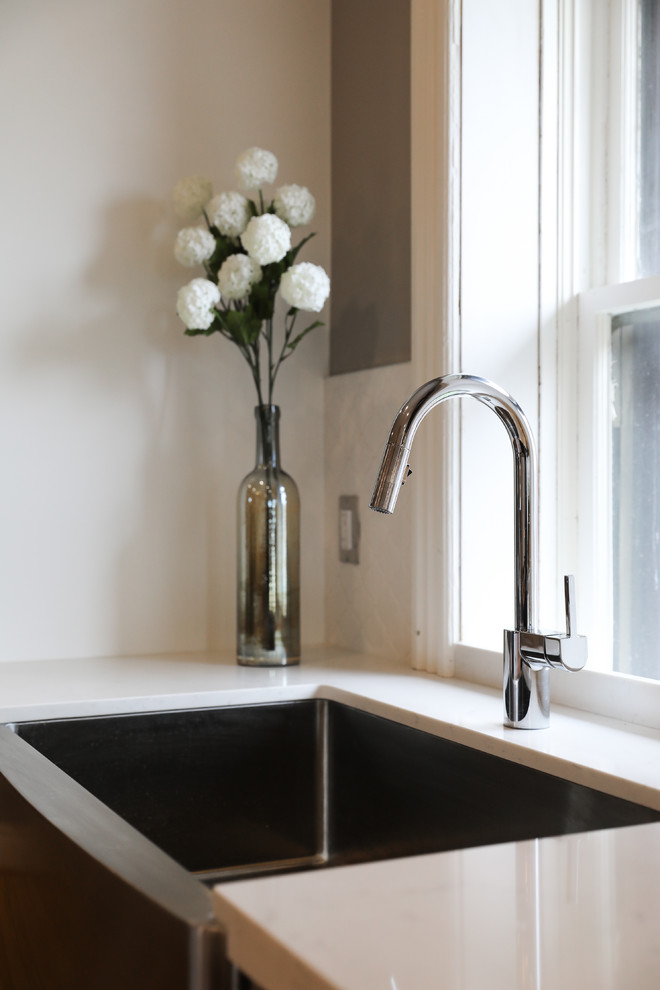 Inspiration for a mid-sized transitional single-wall medium tone wood floor and brown floor eat-in kitchen remodel with a farmhouse sink, shaker cabinets, white cabinets, white backsplash, stainless steel appliances, an island and white countertops