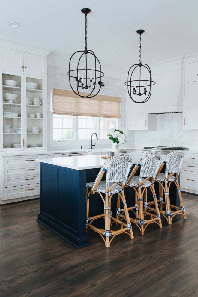 Inspiration for a mid-sized coastal l-shaped medium tone wood floor and brown floor eat-in kitchen remodel in St Louis with a farmhouse sink, shaker cabinets, white cabinets, quartz countertops, white backsplash, marble backsplash, white appliances, an island and white countertops