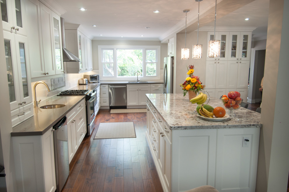 Example of a large transitional u-shaped medium tone wood floor and brown floor eat-in kitchen design in Toronto with a double-bowl sink, shaker cabinets, white cabinets, quartzite countertops, white backsplash, ceramic backsplash, stainless steel appliances and an island