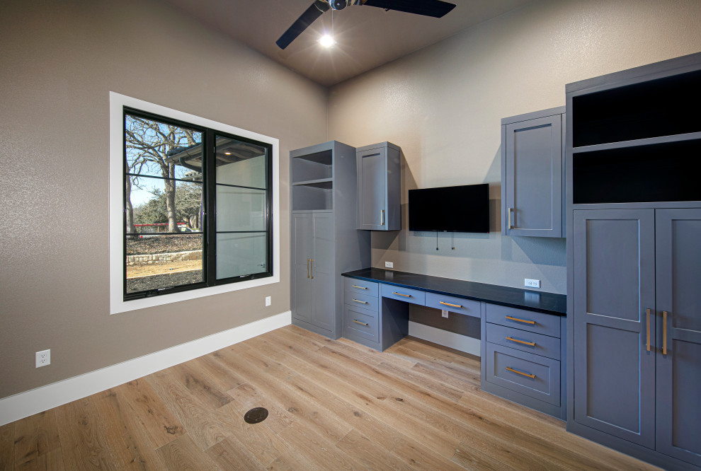 Diseño de despacho tradicional de tamaño medio con paredes grises, suelo de madera clara y escritorio empotrado
