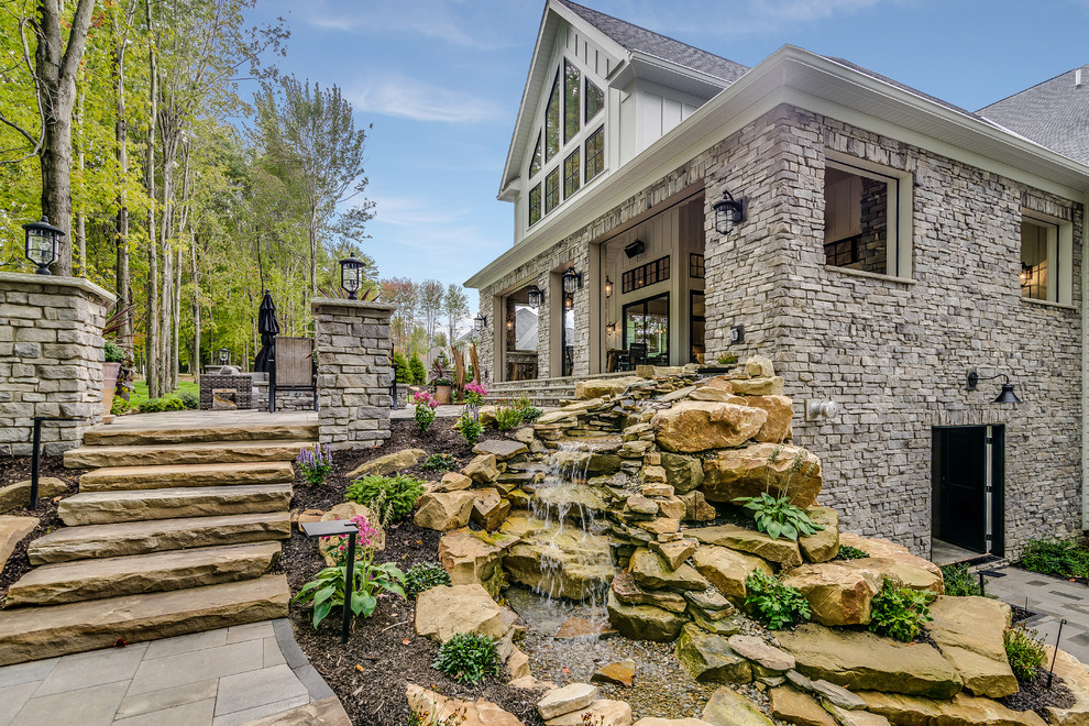 Inspiration for a large transitional backyard partial sun garden for summer in Cleveland with with waterfall and natural stone pavers.