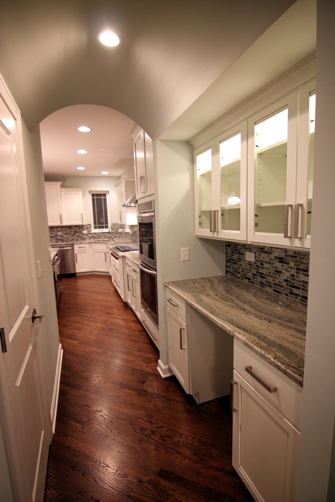 Example of a large transitional single-wall dark wood floor enclosed kitchen design in Chicago with an undermount sink, recessed-panel cabinets, white cabinets, solid surface countertops, multicolored backsplash, matchstick tile backsplash, stainless steel appliances and an island