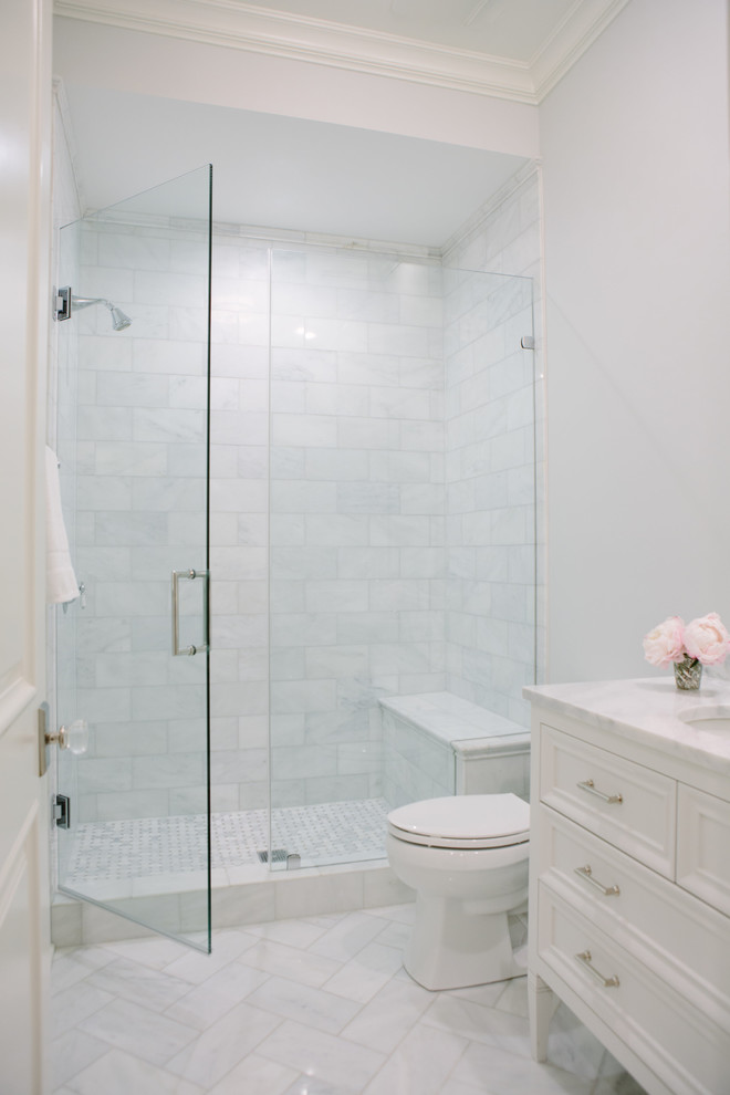 Photo of a transitional bathroom in Chicago with white cabinets, an alcove shower, a two-piece toilet, white tile, grey walls, porcelain floors, an undermount sink, marble benchtops, grey floor, a hinged shower door, white benchtops and recessed-panel cabinets.