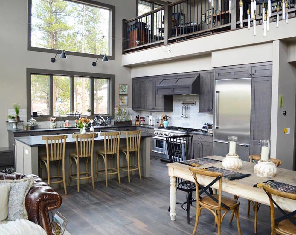 Inspiration for a large country l-shaped open plan kitchen in Denver with an undermount sink, shaker cabinets, grey cabinets, grey splashback, stone tile splashback, stainless steel appliances, dark hardwood floors, with island and grey floor.