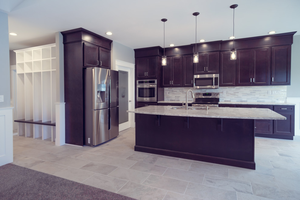 Inspiration for a large transitional u-shaped eat-in kitchen in Boise with a drop-in sink, raised-panel cabinets, dark wood cabinets, granite benchtops, grey splashback, subway tile splashback, stainless steel appliances, ceramic floors and with island.