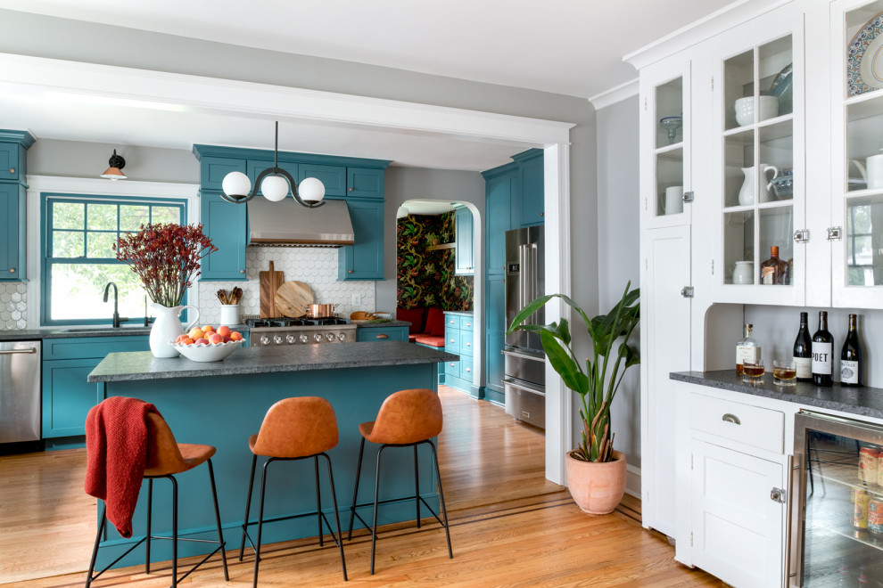 This is an example of a medium sized bohemian single-wall kitchen/diner in Philadelphia with a submerged sink, shaker cabinets, blue cabinets, granite worktops, white splashback, ceramic splashback, stainless steel appliances, light hardwood flooring, an island, orange floors and grey worktops.