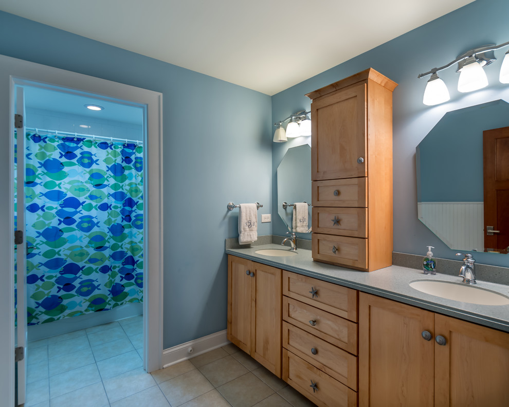 Small traditional 3/4 bathroom in Chicago with flat-panel cabinets, light wood cabinets, an alcove tub, a shower/bathtub combo, blue walls, ceramic floors, a drop-in sink, limestone benchtops, white floor, a shower curtain, a one-piece toilet, blue tile, ceramic tile, grey benchtops, a double vanity, a freestanding vanity, wallpaper and wallpaper.